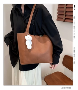 Brown tote bag in lychee pattern leather with cute white bear pendant shown in a room