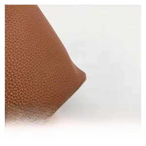 Detailed close-up showing high-quality brown litchi grain texture on the leather tote bag
