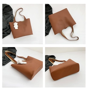 Detail view of large brown tote bag with litchi texture and cute bear pendant