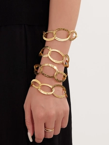 Dettaglio di bracciali a catena dorati martellati e anello con perla elegante