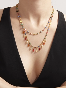 Detail of layered gold necklace with colorful evil eye beads and teardrop pendants