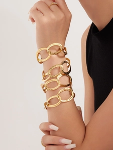 Dettaglio del bracciale a catena dorata a doppio strato con finitura martellata sul polso