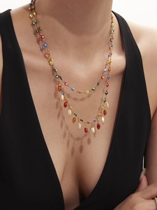 Detail of layered gold evil eye necklace with colorful beads and resin drop charms