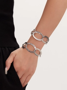 Dettaglio dei braccialetti a doppio strato in metallo martellato argento su modella