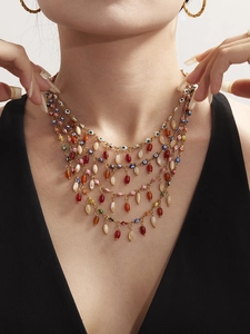 Detailed close-up of layered gold chain necklace featuring colorful evil eye beads