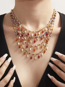 Detail of layered gold evil eye necklace with vibrant colorful enamel beads on model