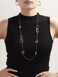 Dettaglio della collana in catena d'oro con pietre blu a goccia e ciondoli ovali