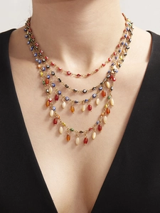 Detail of multi-layered gold necklace with colorful evil eye charms and teardrop beads