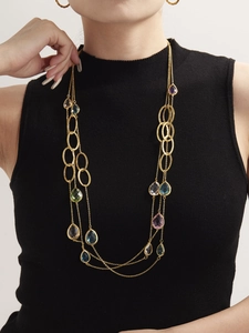 Dettaglio di collana dorata a strati con pietre colorate a goccia e maglie martellate