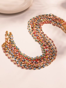 Detailed macro of gold chains featuring colorful enamel evil eye charms in vivid colors