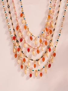 Detail of gold evil eye necklace featuring colorful enamel beads and layered resin charms