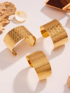 Λεπτομέρεια από τρία επίχρυσα 18k ατσάλινα βραχιόλια με μοναδικά ανάγλυφα φλοράλ σχέδια