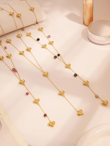 Detail of long gold heart necklaces with colorful stone beads and heart charms