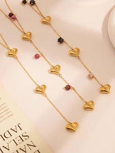 Detailed macro of gold heart charms and colorful natural stone beads on a long necklace