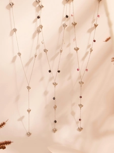 Macro detail of Y-shape stainless steel necklaces with silver hearts and natural stones