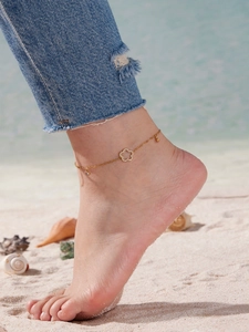 Detail der Fußkette mit Blumenanhänger und 5A-Zirkonia auf Sand mit Muscheln