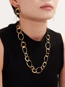 Gros plan d'un ensemble collier et boucles d'oreilles géométriques dorés sur un mannequin