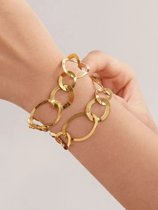 Gros plan d'un bracelet doré à maillons ovales géométriques porté au poignet
