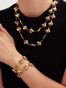 Detailed close-up of 18k gold plated hollow heart necklace and bracelet jewelry set