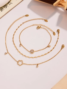 Detaillierte Ansicht von drei goldenen Edelstahl-Fußkettchen mit Zirkonia-Blumenanhängern