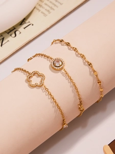 Detailaufnahme von dreiteiligen goldenen Fußkettchen mit glitzernden Zirkonia-Blüten
