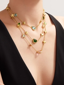 Close-up of layered 18k gold heart necklace with vibrant faceted gemstones on model