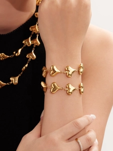 Detail of 18K gold plated heart necklace and bracelet set worn on black turtleneck