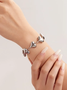 Detailed view of silver heart-shaped chain bracelet with high-polish finish on wrist