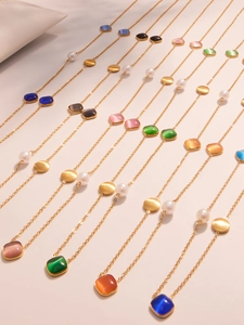 Macro detail of rainbow cat eye beads and gold coins on stainless steel necklaces
