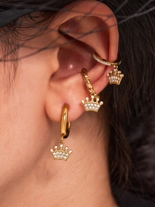Nahaufnahme von drei 18k vergoldeten Kronen-Ohrringen mit Zirkonia am Ohr eines Models