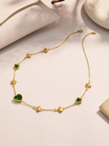 Close-up of 18k gold heart necklace featuring green faceted stone and adjustable chain
