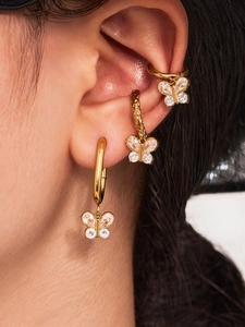 Gros plan de boucles d'oreilles papillon dorées avec zircons et manchette d'oreille martelée