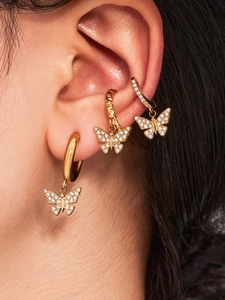 Gros plan détaillé des boucles d'oreilles papillon plaqué or 18k et du ear cuff serti de zircons