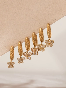 Détail de boucles d'oreilles papillon en or 18 carats avec texture martelée et strass