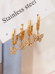 Gros plan sur des créoles en acier doré 18 carats avec pendentifs papillon en strass
