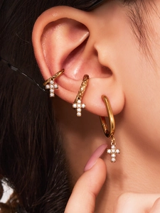 Gros plan de boucles d'oreilles croix dorées et bagues d'oreille avec zircons blancs