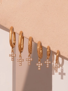 Détail de boucles d'oreilles croix dorées serties de zircons 5A sur support velours