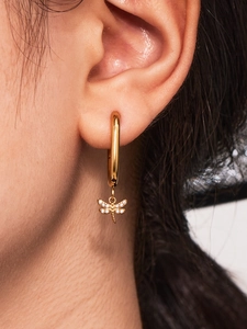 Macro view of gold dragonfly hoop earring with micro-pave zircons worn on the ear