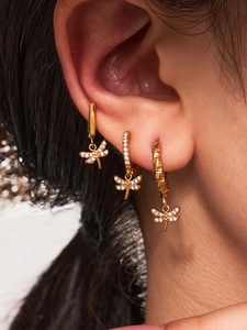 Macro detail of gold dragonfly earrings with micro-paved cubic zirconia in a stacked style