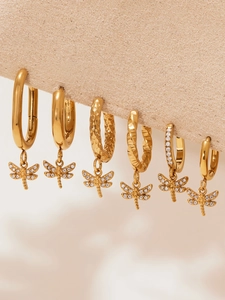 Macro shot of gold dragonfly earrings set with pavé cubic zirconia and textured hoops