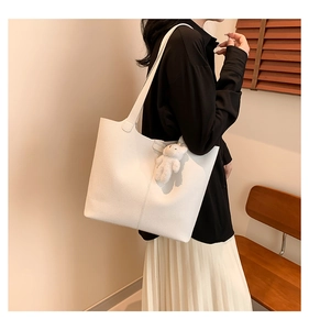 White lychee grain tote bag with plush bear charm shown on model in a cozy setting