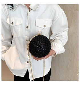 Detail of spherical black sequin evening bag with gold ring closure and chain strap