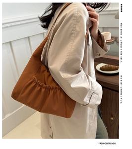 Detail of a brown pleated shoulder bag showing delicate ruching and metallic zipper