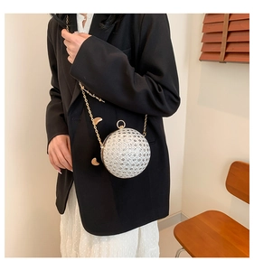 Detailed view of spherical white evening bag with gold chain and ring handle on model