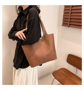 Detail of caramel pebbled leather texture and vertical stitching on a large tote bag