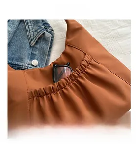 Detail of the caramel tote bag featuring a side elastic pleated pocket with glasses