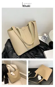Detail of khaki pebbled leather tote bag with wide strap and teddy bear charm accessory