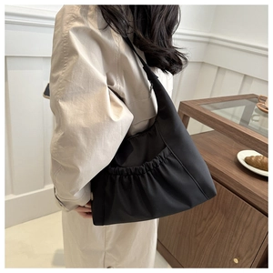 Close-up of black pleated nylon shoulder bag with spacious pockets on model
