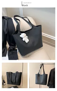 Detail of black pebbled leather tote bag with a cute white plush bear keychain