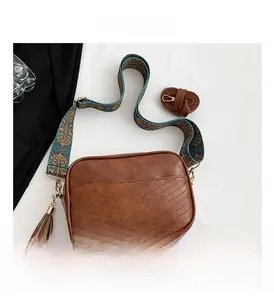 Detail of vintage brown textured leather bag with V-stitch and bohemian wide strap